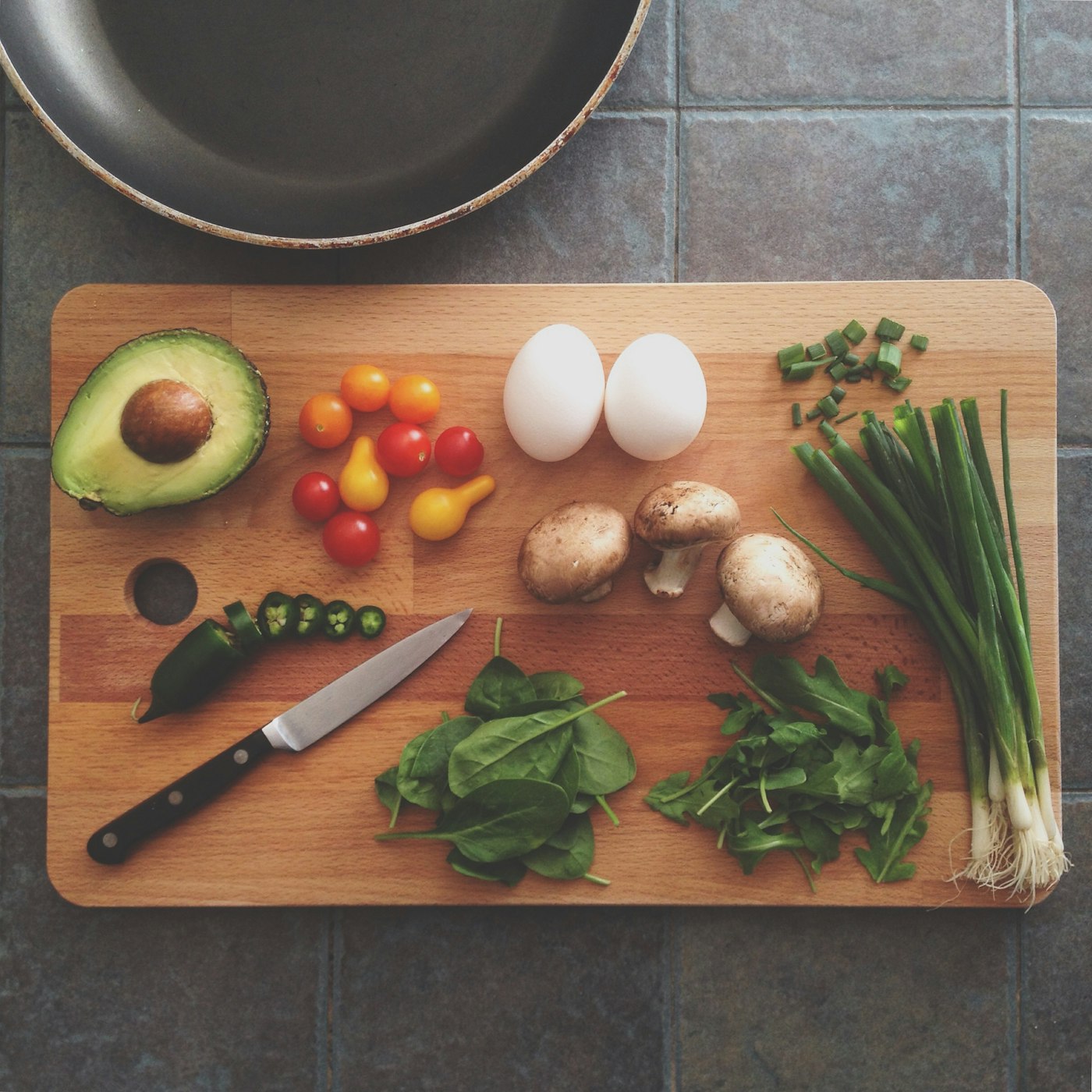 Tábua com ingredientes frescos e faca de cozinha